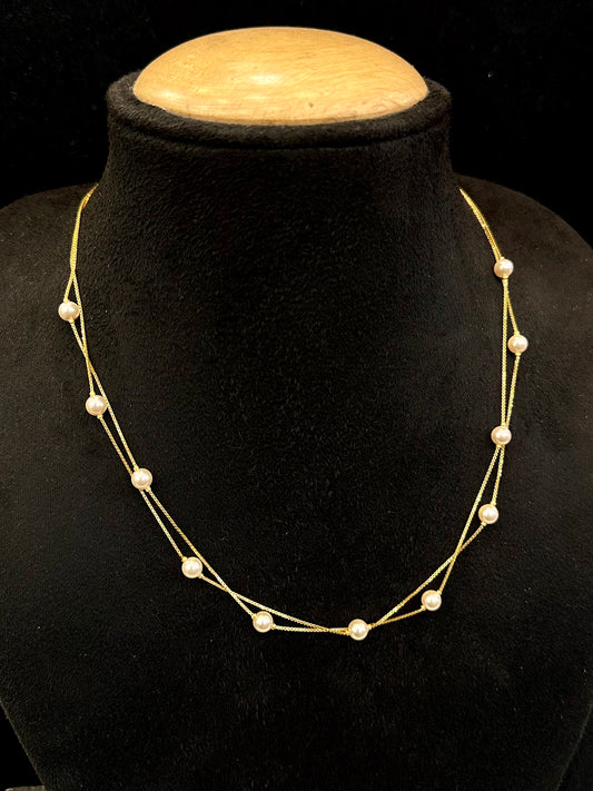 Gold necklace with pearls on a black stand