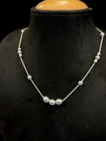 Pearl necklace on a black mannequin bust with a wooden base.