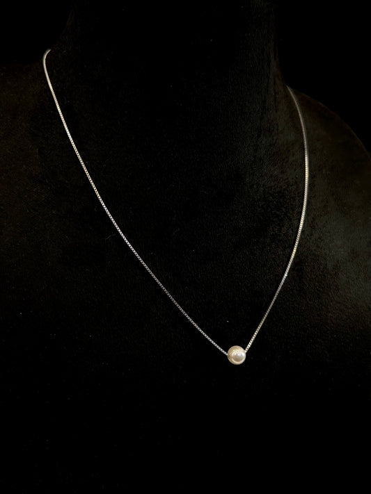 Necklace with a single pearl pendant on a black background