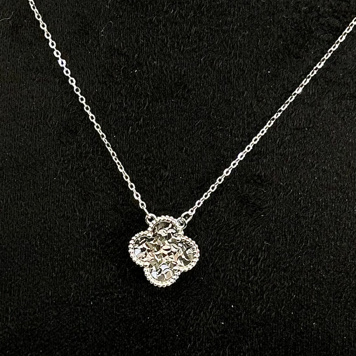 Silver necklace with a floral pendant on a black background