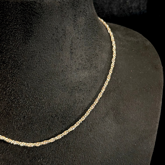 Gold necklace on a black mannequin with a wooden base