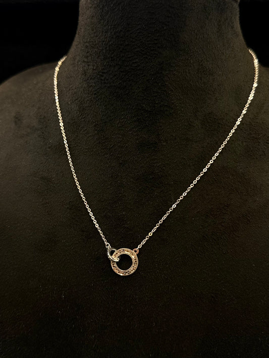 Necklace with a circular pendant on a black mannequin bust
