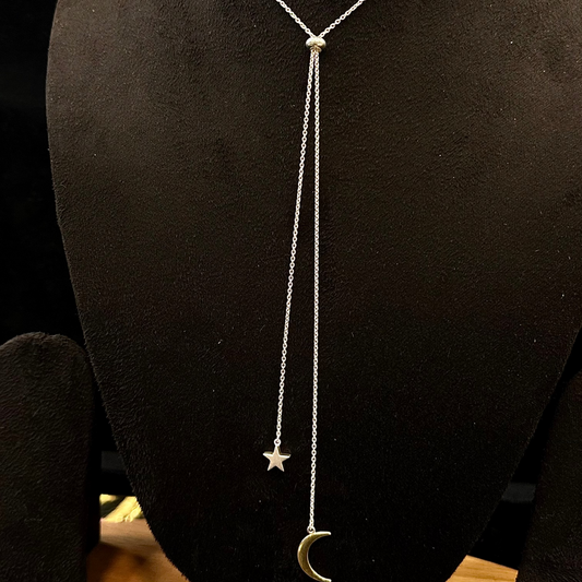 Silver necklace with star and moon charms on a black mannequin bust.