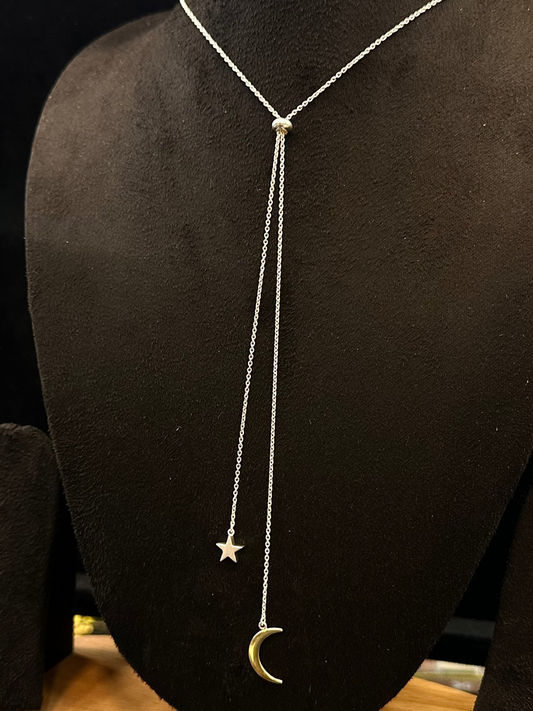 Necklace with star and moon pendants on a black mannequin bust.