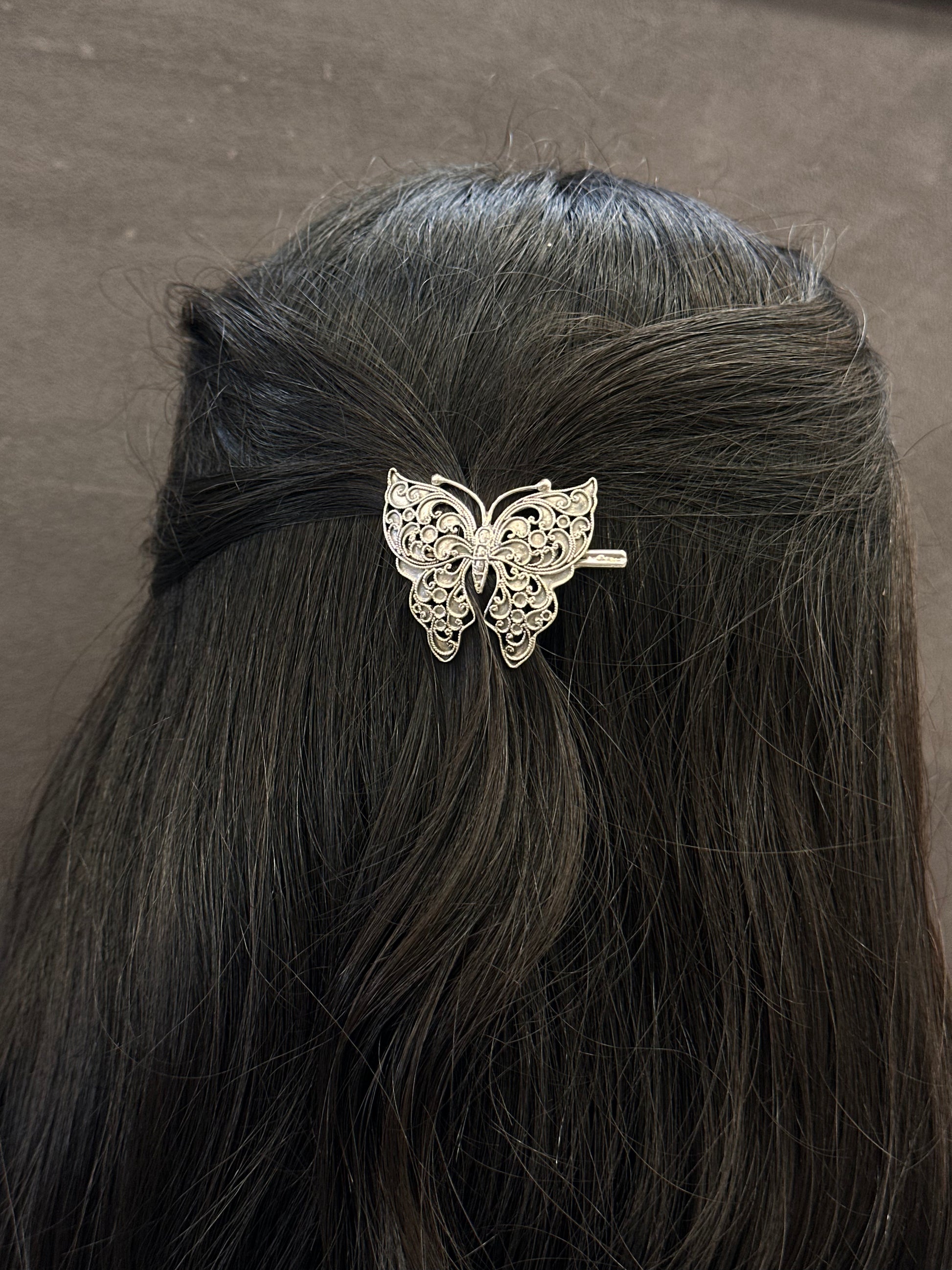 Butterfly hair clip on a person's hair against a neutral background