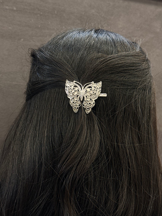 Butterfly hair clip on a person's hair against a neutral background