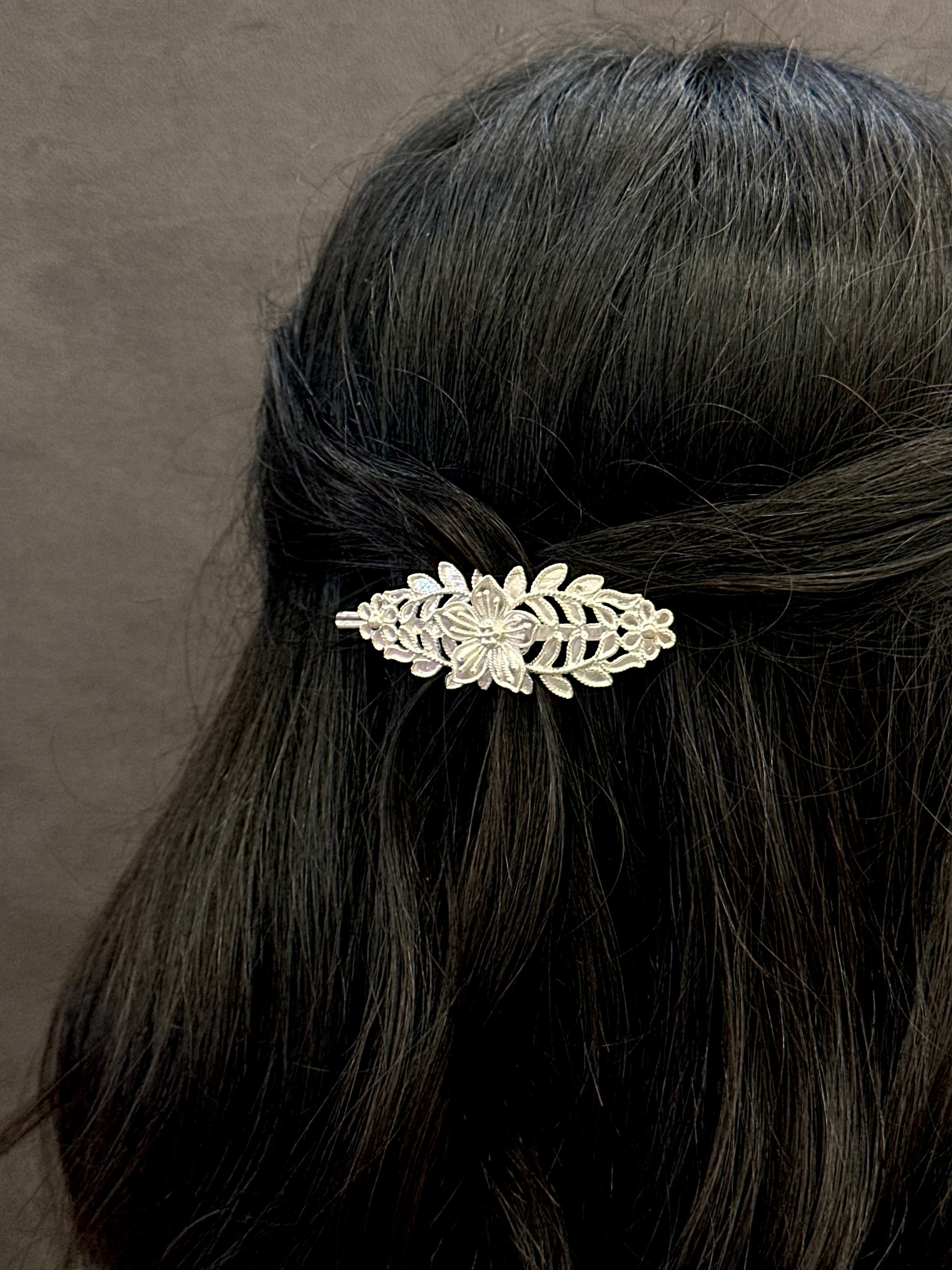 Decorative hair clip in a person's hair against a neutral background