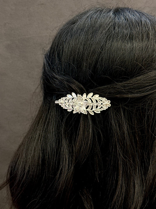 Decorative hair clip in a person's hair against a neutral background