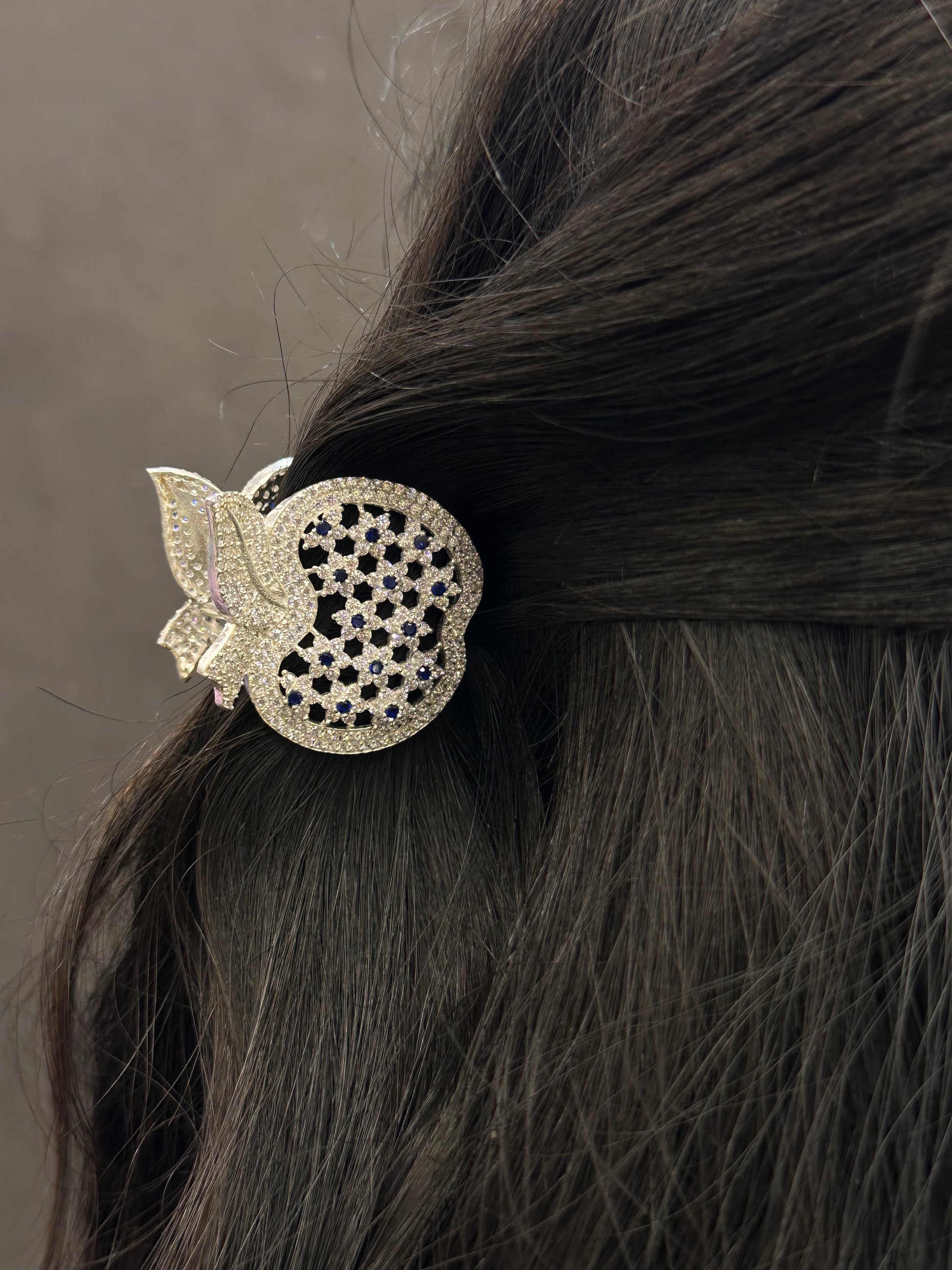 Decorative hair clip with intricate design on dark hair against a neutral background