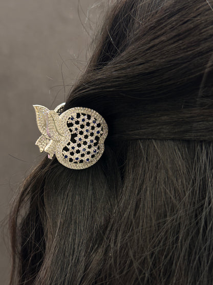 Decorative hair clip with intricate design on dark hair against a neutral background