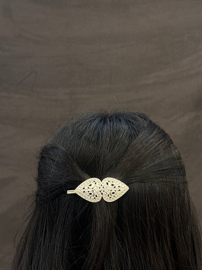hair clip with leaf design on black hair against a brown background