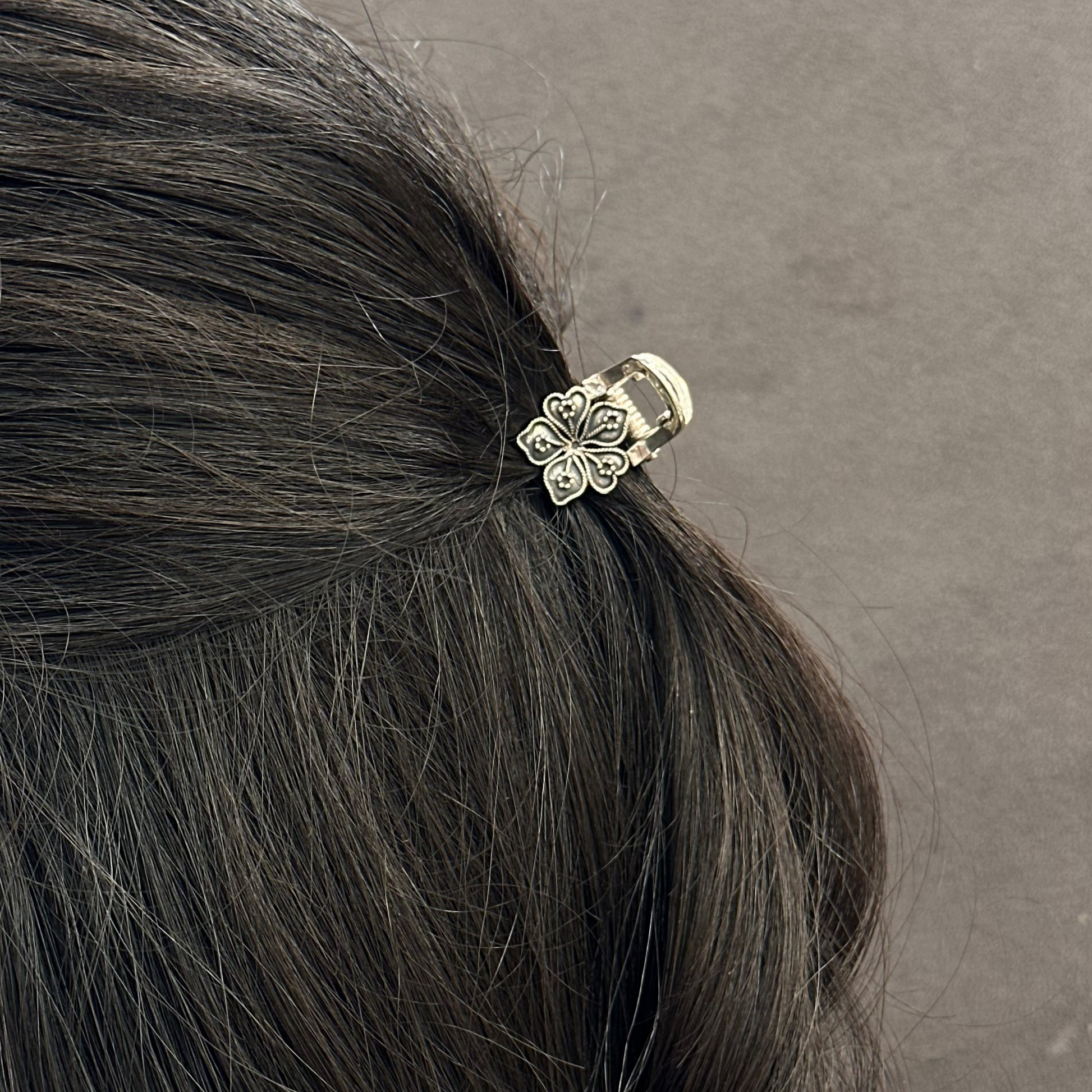 Hair tie with floral design in a person's hair against a gray background
