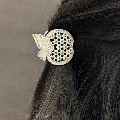 Decorative hair clip with black and clear gemstones on dark hair against a neutral background