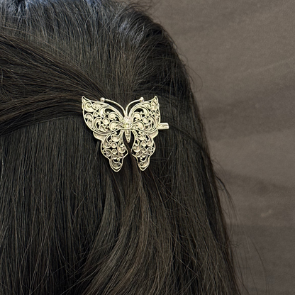 Butterfly hair clip on black hair against a gray background