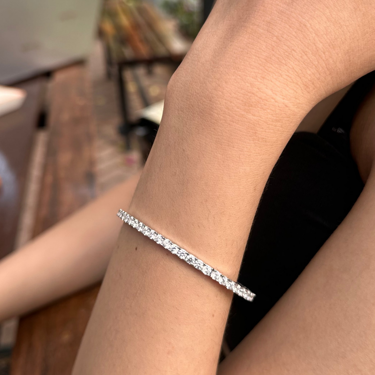 Silver bracelet on a wrist with a blurred outdoor background