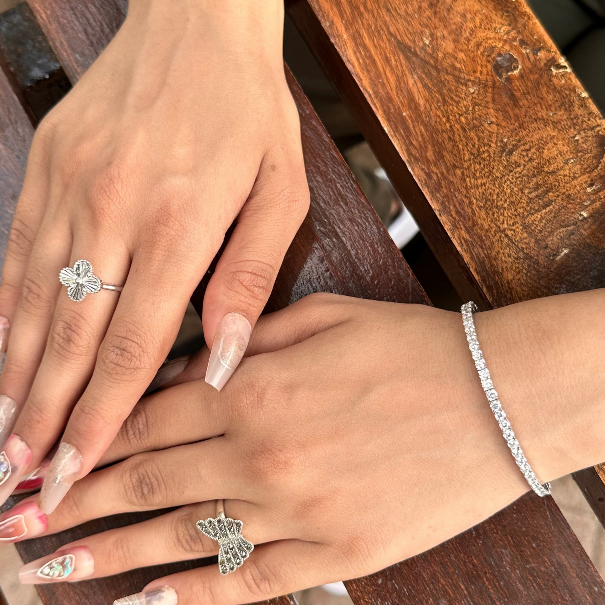 Two hands with rings on a wooden surface